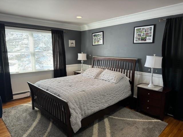 bedroom featuring baseboard heating, wood-type flooring, and crown molding