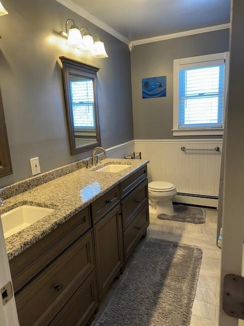 bathroom featuring a baseboard radiator, ornamental molding, a wealth of natural light, and vanity