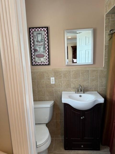 bathroom featuring vanity, tile patterned floors, tile walls, and toilet