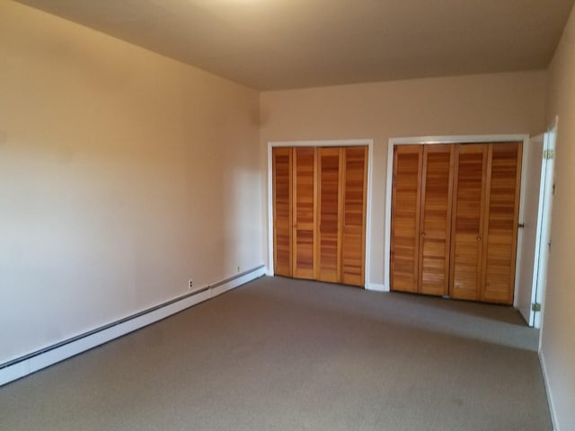 unfurnished bedroom featuring a baseboard radiator, carpet, and two closets