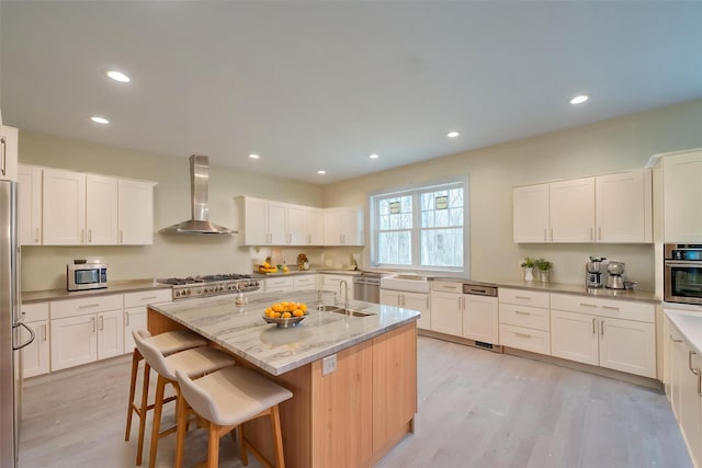 597 Pulaski, Kings Park, NY 11754 - kitchen with an island with sink, stainless steel appliances, wall chimney range hood, light wood-style flooring, and a breakfast bar area