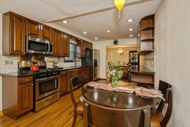 kitchen with backsplash, appliances with stainless steel finishes, sink, and light wood-type flooring