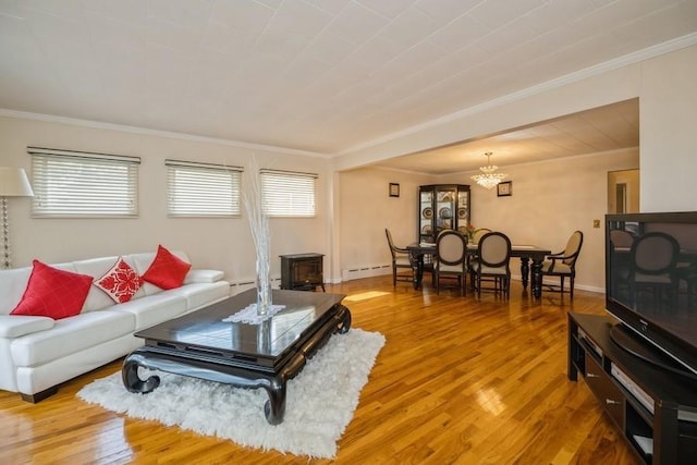 living room featuring hardwood / wood-style floors, a wood stove, a baseboard heating unit, crown molding, and an inviting chandelier