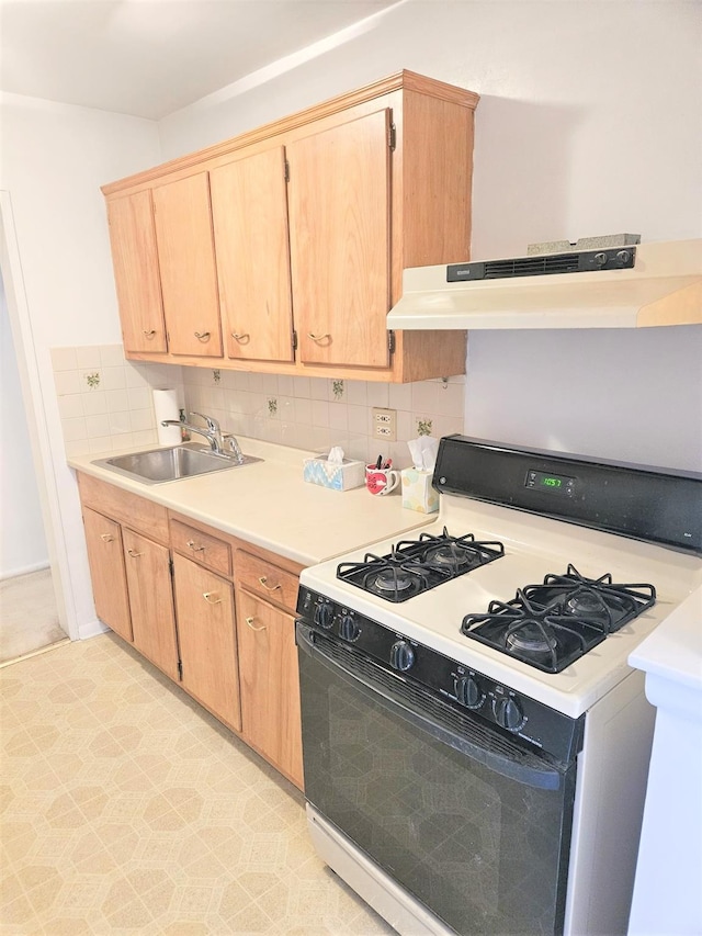 kitchen with light brown cabinetry, sink, backsplash, and range with gas stovetop