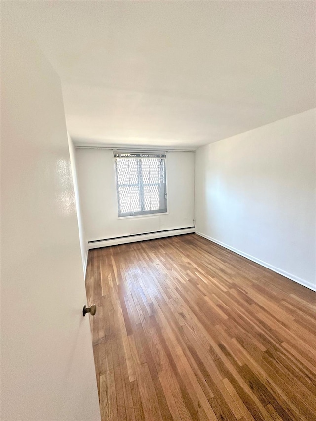 unfurnished room featuring hardwood / wood-style floors and baseboard heating