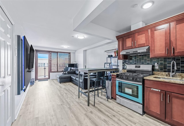 kitchen with stone counters, stainless steel range with gas cooktop, sink, backsplash, and light wood-type flooring