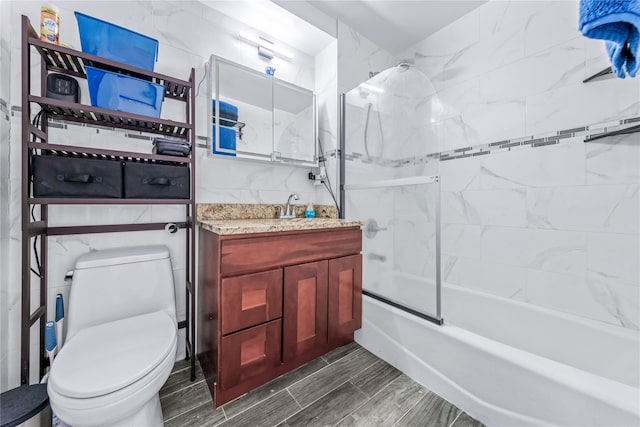 full bathroom with vanity, tile walls, shower / bath combination with glass door, and toilet