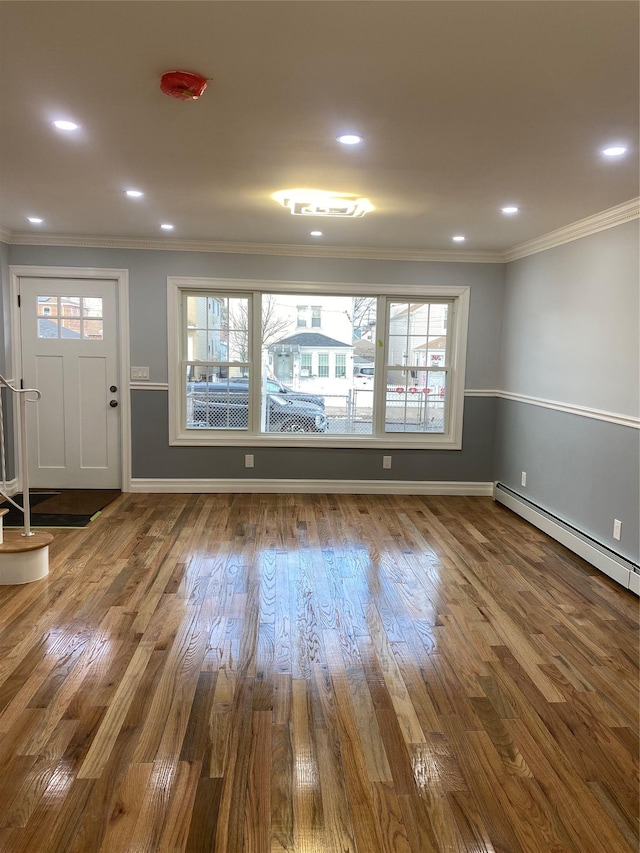 interior space with hardwood / wood-style flooring, crown molding, and baseboard heating