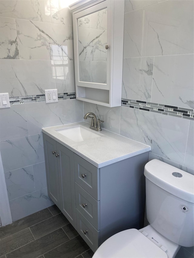 bathroom featuring tile walls, vanity, and toilet