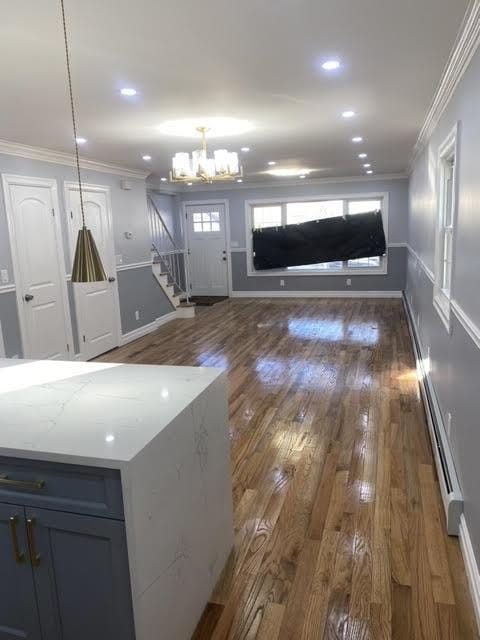 kitchen featuring hanging light fixtures, a baseboard radiator, ornamental molding, and dark hardwood / wood-style floors