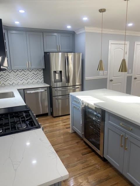 kitchen with dark hardwood / wood-style floors, pendant lighting, beverage cooler, backsplash, and stainless steel appliances