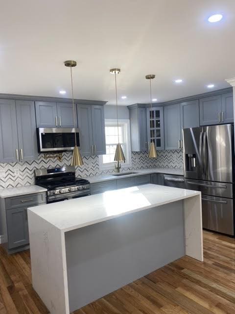 kitchen with sink, decorative light fixtures, stainless steel appliances, and a center island