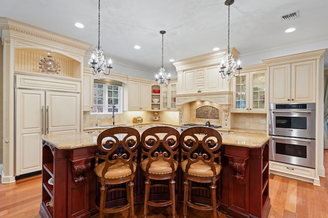 kitchen with stainless steel appliances, cream cabinets, a center island, and light stone counters