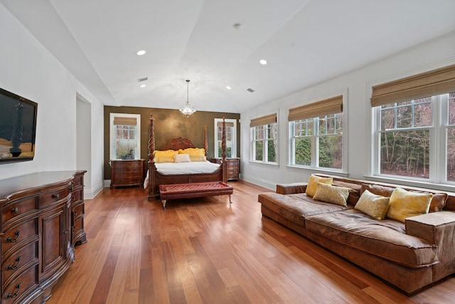 bedroom with lofted ceiling, a notable chandelier, and light wood-type flooring