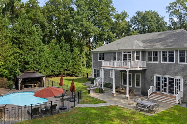 back of house featuring a patio, a balcony, a yard, a fenced in pool, and a gazebo