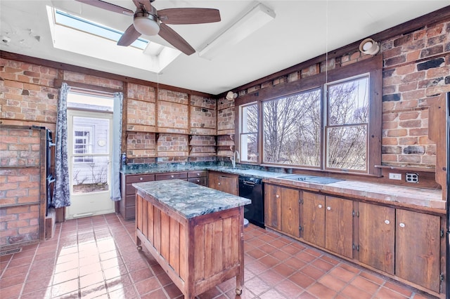 kitchen with brick wall, a tray ceiling, a skylight, and a center island