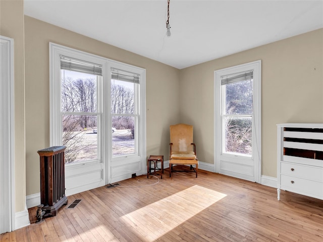 living area featuring light wood-type flooring, visible vents, and baseboards