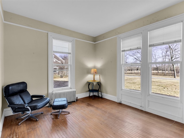 sitting room featuring baseboards, light wood-style flooring, and radiator heating unit