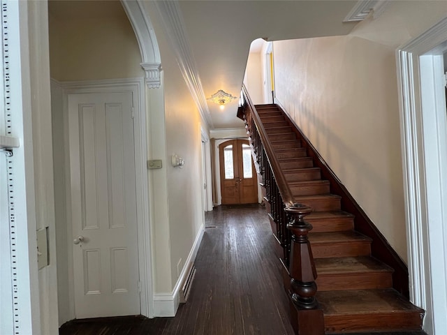 staircase featuring arched walkways, baseboards, and wood finished floors