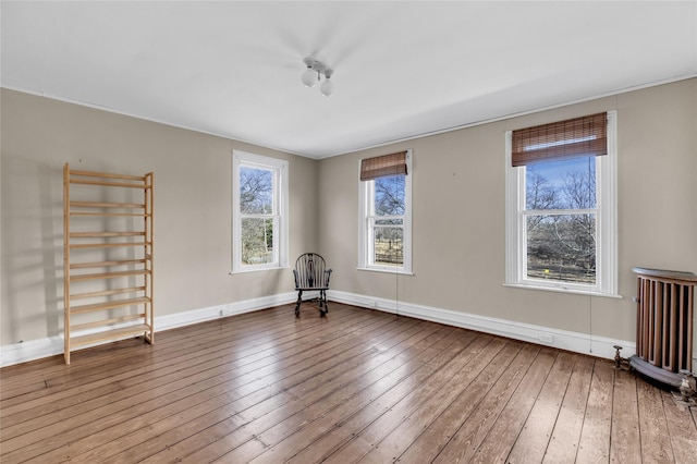 unfurnished room with radiator, baseboards, and wood finished floors