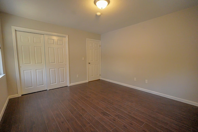 unfurnished bedroom with dark hardwood / wood-style flooring and a closet