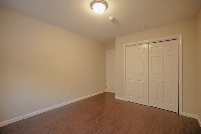 unfurnished bedroom with dark wood-type flooring and a closet