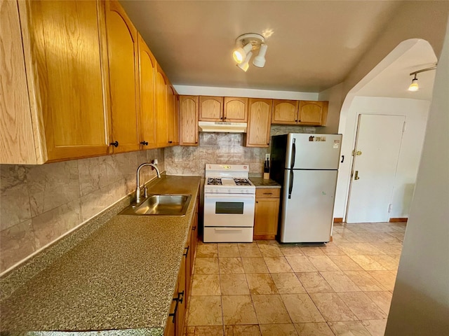 kitchen featuring sink, decorative backsplash, white gas range oven, and stainless steel refrigerator