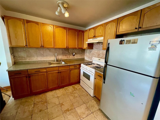 kitchen featuring tasteful backsplash, sink, stainless steel fridge, and white range with gas stovetop