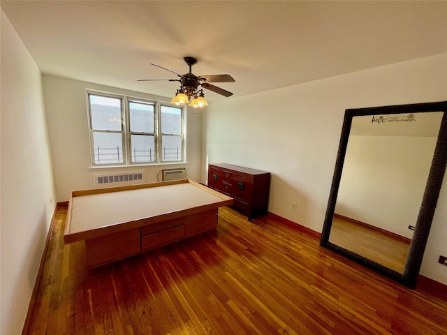 bedroom with ceiling fan, radiator, a wall unit AC, and dark hardwood / wood-style flooring