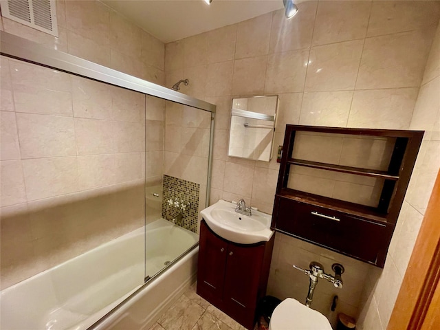 full bathroom featuring tile walls, vanity, bath / shower combo with glass door, and toilet