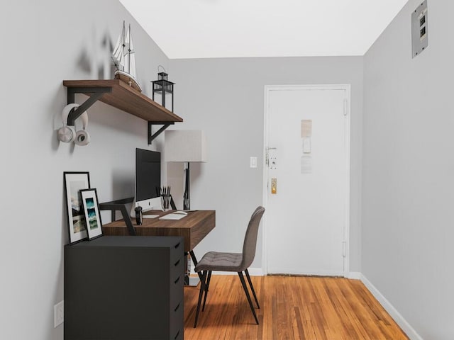 home office with baseboards and wood finished floors