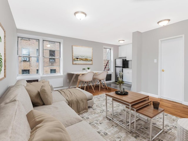 living room with a wealth of natural light, light wood-type flooring, and baseboards