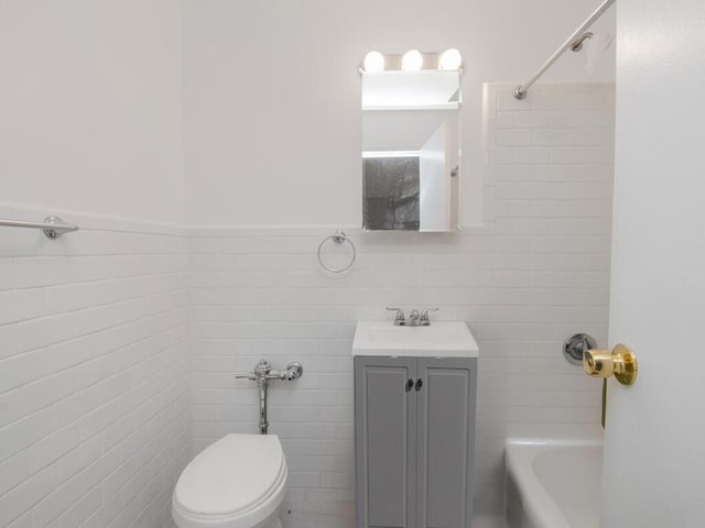 bathroom featuring toilet, a wainscoted wall, vanity, shower / washtub combination, and tile walls