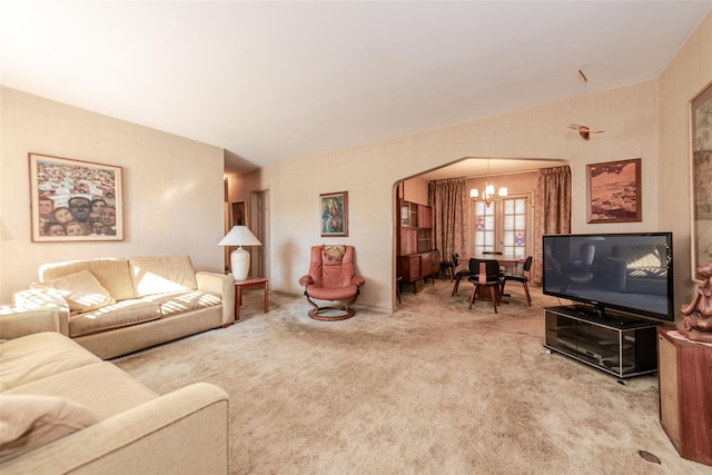 carpeted living room with an inviting chandelier