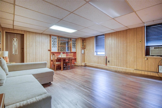 living room with a paneled ceiling, hardwood / wood-style floors, and wood walls