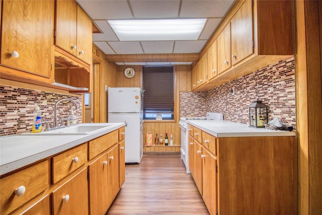 kitchen featuring sink, white appliances, tasteful backsplash, light hardwood / wood-style floors, and a drop ceiling