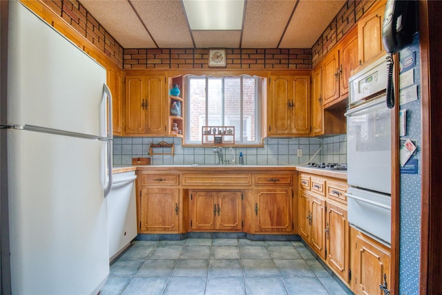 kitchen featuring tasteful backsplash, sink, light tile patterned floors, and white appliances