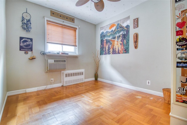 empty room with light parquet floors, a wall mounted air conditioner, radiator heating unit, and ceiling fan