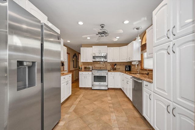 kitchen with stone counters, white cabinetry, hanging light fixtures, appliances with stainless steel finishes, and decorative backsplash