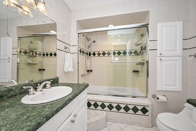 full bathroom with bath / shower combo with glass door, vanity, toilet, and tile walls