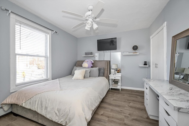 bedroom featuring dark wood-type flooring, a baseboard radiator, and ceiling fan