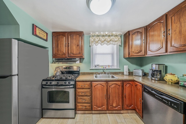 kitchen with appliances with stainless steel finishes, sink, and light hardwood / wood-style flooring