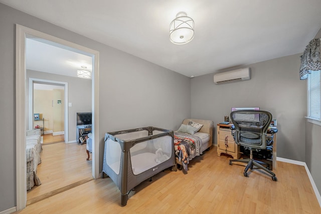 bedroom featuring hardwood / wood-style flooring and a wall unit AC