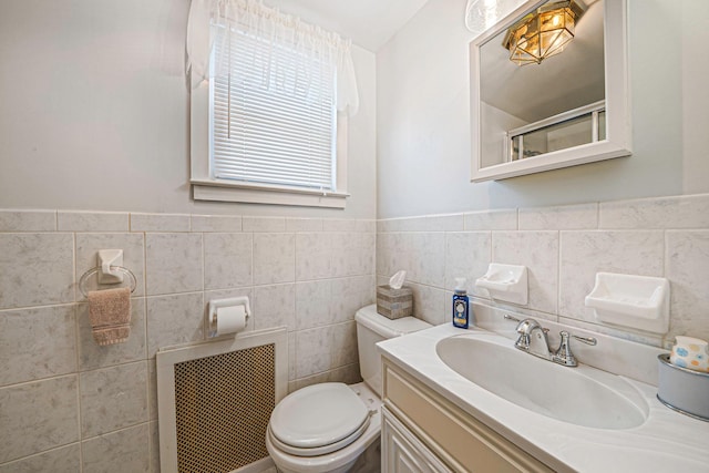 bathroom featuring vanity, radiator, tile walls, and toilet