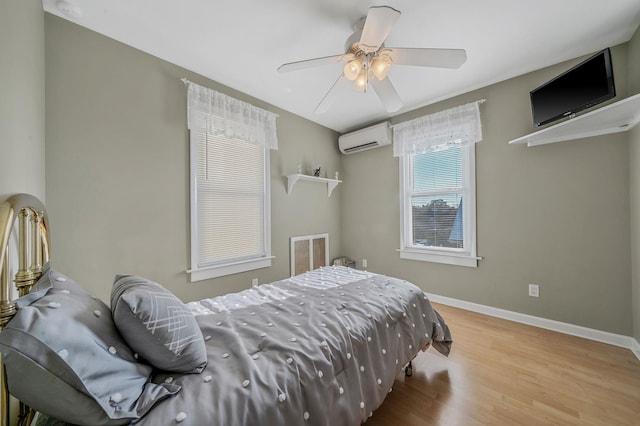 bedroom featuring a wall mounted AC, ceiling fan, and light hardwood / wood-style flooring