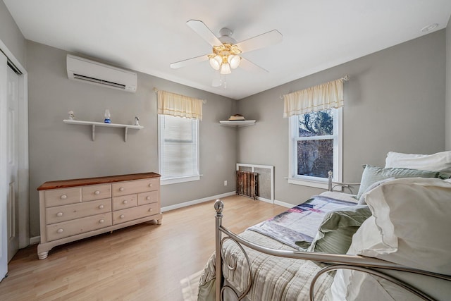 bedroom with multiple windows, ceiling fan, an AC wall unit, and light hardwood / wood-style floors