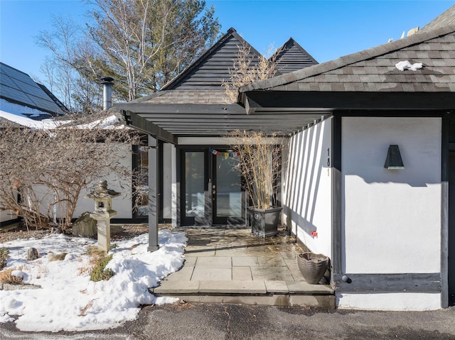 snow covered property entrance with a patio