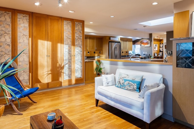 living area with a skylight and light wood-type flooring