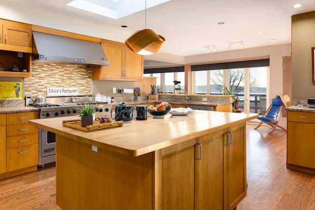 kitchen featuring light hardwood / wood-style flooring, butcher block counters, a center island, tasteful backsplash, and extractor fan