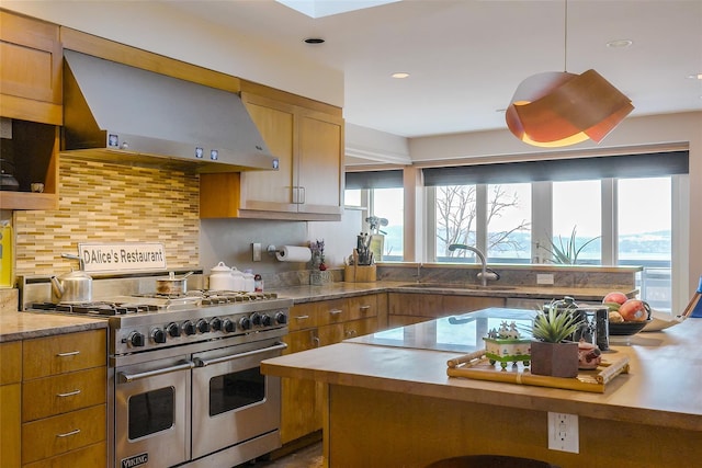 kitchen featuring decorative light fixtures, sink, backsplash, range with two ovens, and wall chimney range hood